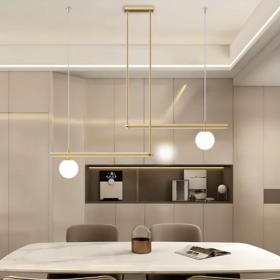 Luminaire doré à lignes décalées et deux globes opalins, suspendu dans une salle à manger moderne et épurée