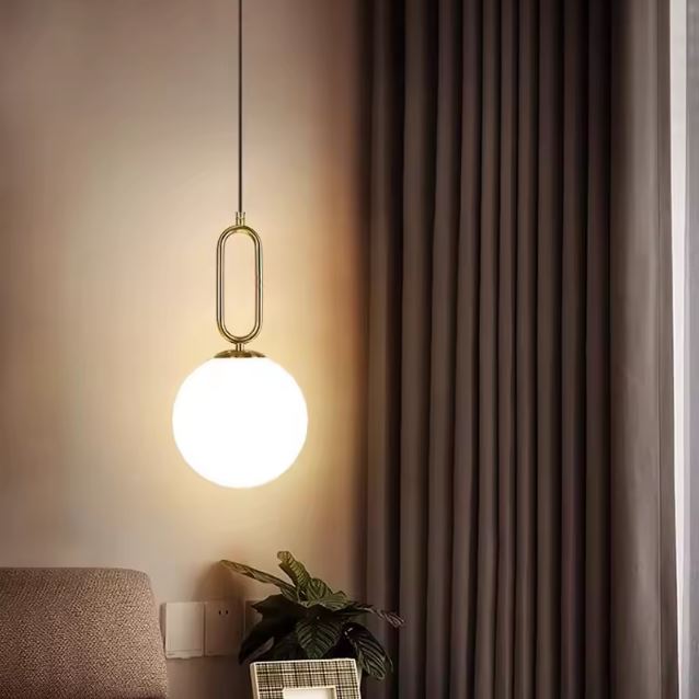 Suspension globe blanc en laiton au style japandi moderne, luminaire décoratif créant une lumière douce et apaisante.