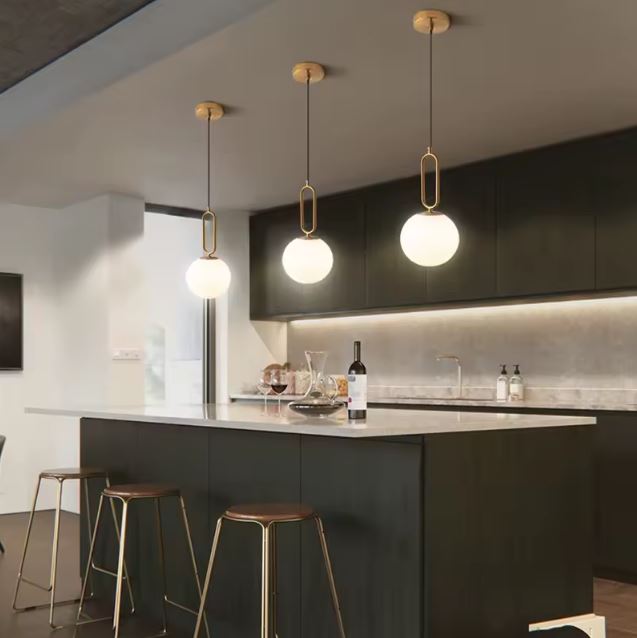 Suspension globe opaline en laiton au style scandinave moderne, luminaire élégant idéal au-dessus d’un îlot de cuisine design.