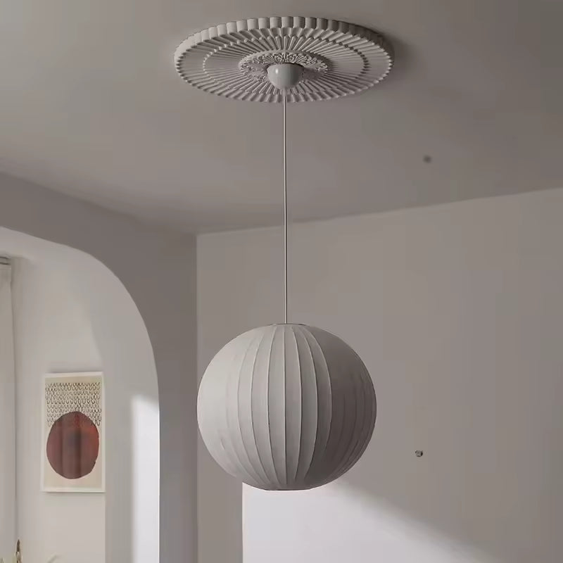 Suspension globe plissée en soie blanche au design contemporain et épuré, mise en valeur sous une rosace décorative
