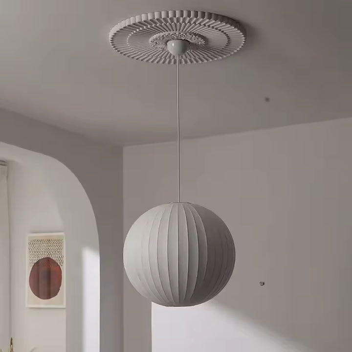 Suspension globe plissée en soie blanche au design contemporain et épuré, mise en valeur sous une rosace décorative