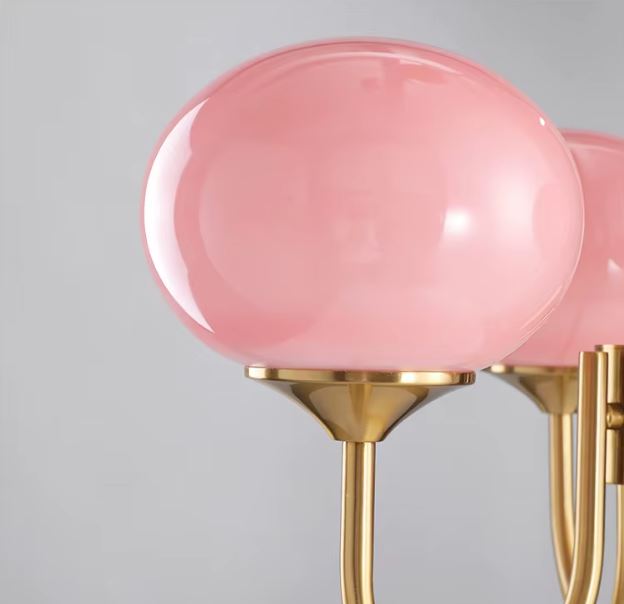 Détail de suspension globe rose opalin sur structure en laiton, luminaire mid-century aux accents doux et raffinés.
