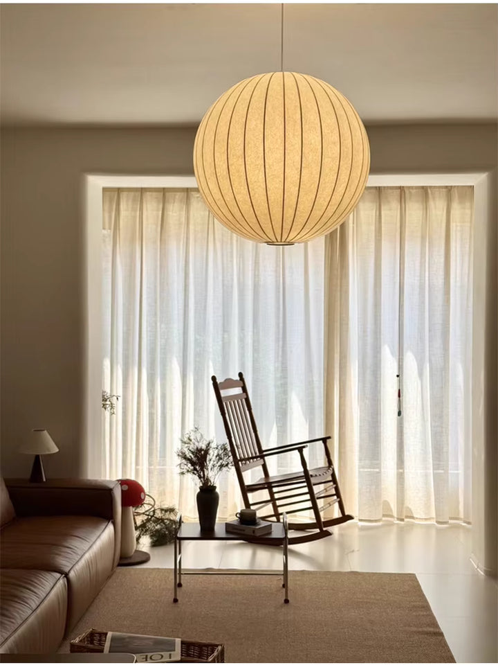 Suspension globe en soie blanche au style wabi-sabi et japonais, diffusant une lumière douce dans un salon aux tons chaleureux