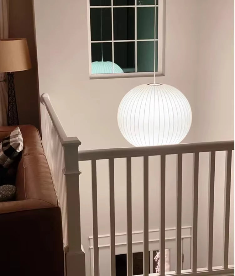Suspension globe en soie blanche plissée au style contemporain, éclairant avec douceur une cage d’escalier élégante