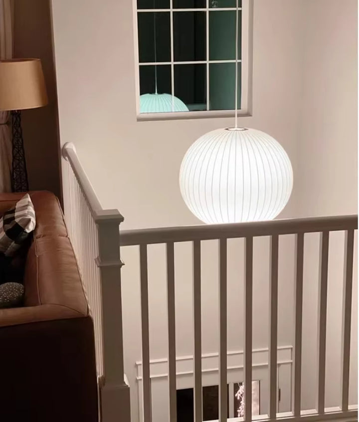 Suspension globe en soie blanche plissée au style contemporain, éclairant avec douceur une cage d’escalier élégante