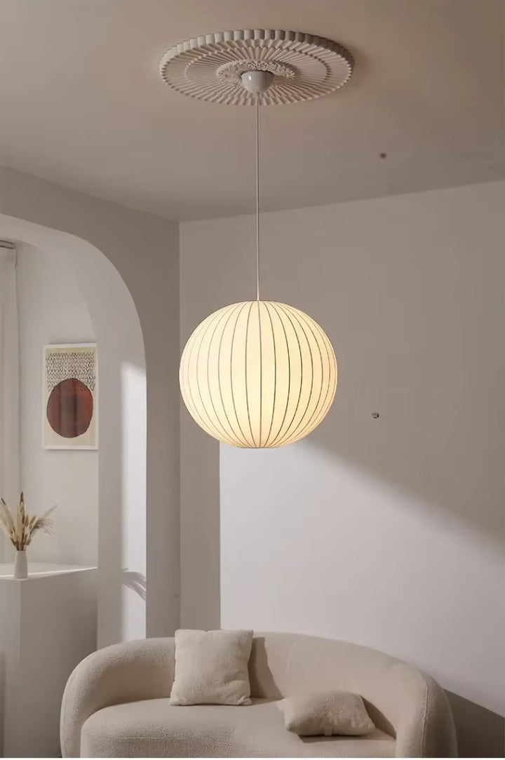 Suspension globe en soie blanche plissée au style cocooning et minimaliste, diffusant une lumière chaleureuse dans le salon
