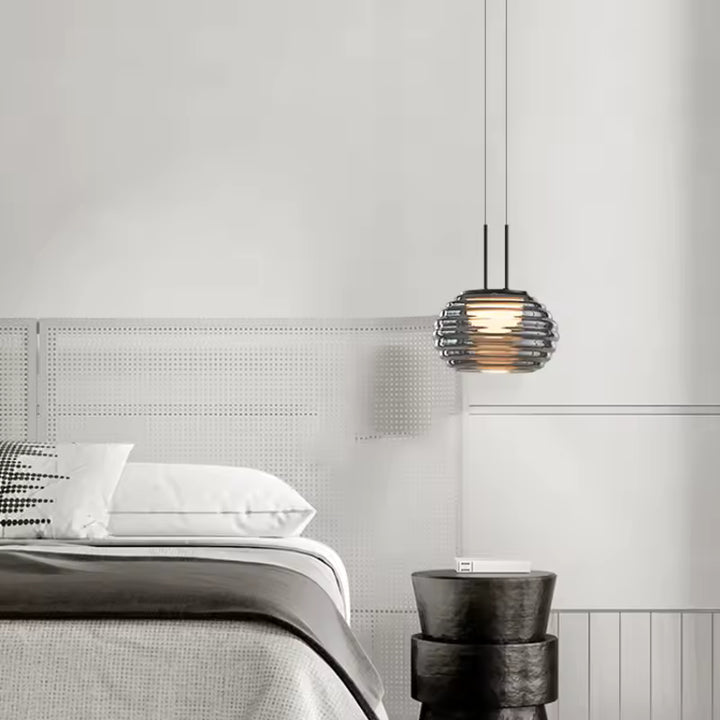 Suspension globe strié en verre fumé utilisée en chevet, dans une chambre contemporaine aux tons sobres