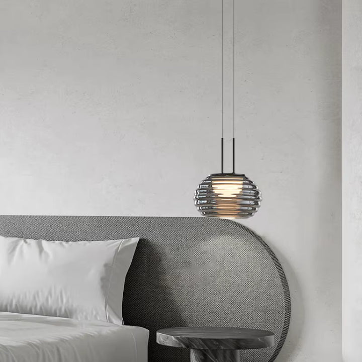 Suspension globe strié en verre fumé près du lit, dans une chambre contemporaine aux lignes douces et organiques