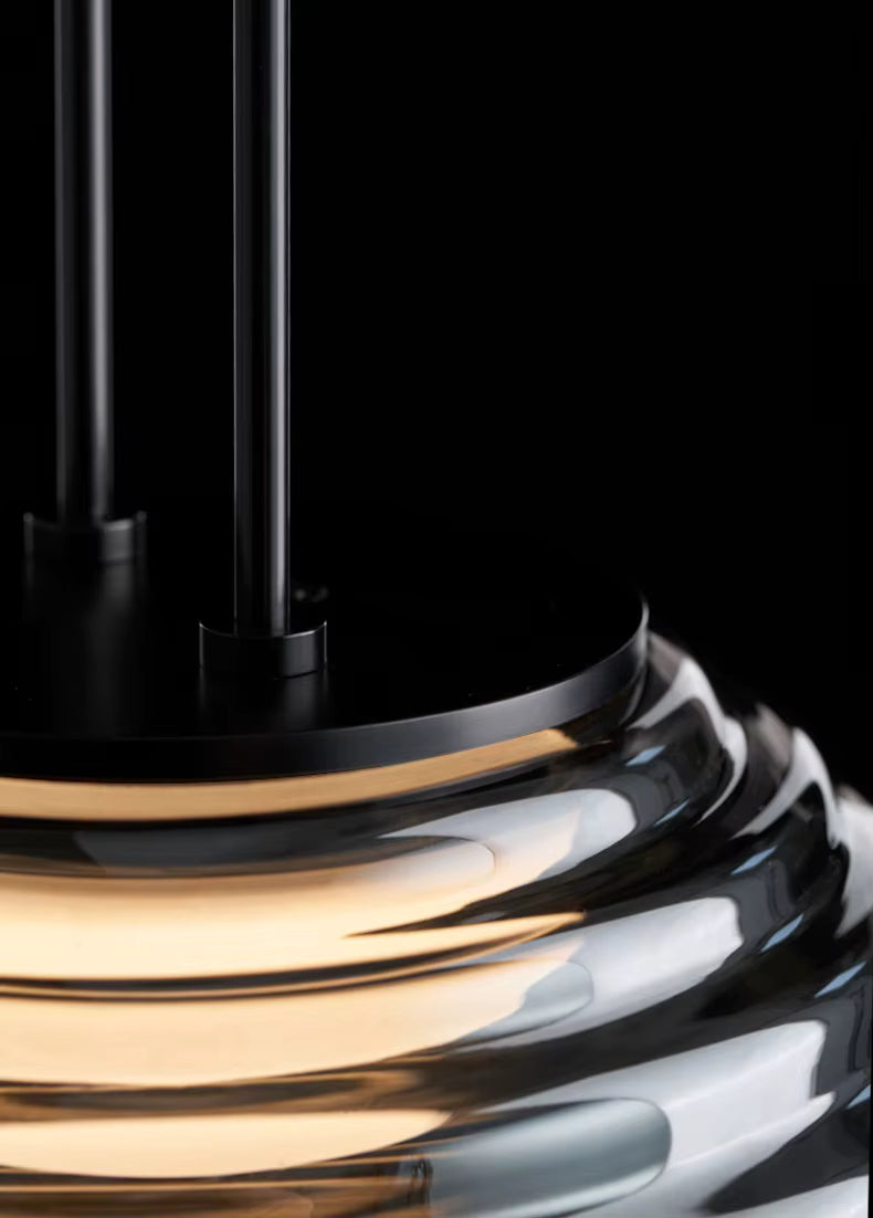 Détail de la suspension globe en verre fumé strié, avec finition noire et reflets lumineux sophistiqués
