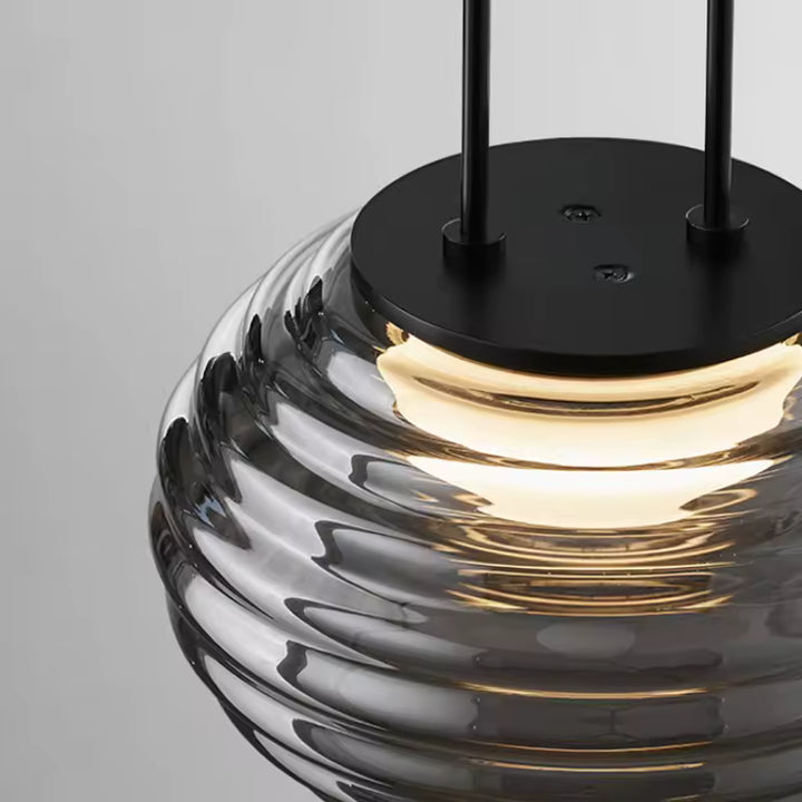 Détail de la suspension globe en verre fumé strié, avec fixation noire et lumière chaude au style contemporain