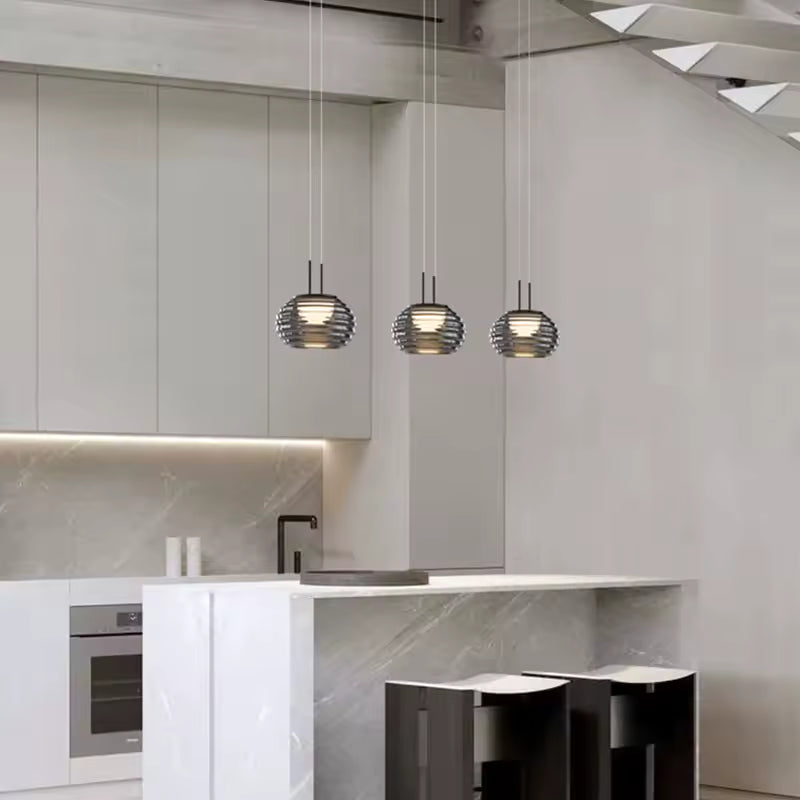 Trois suspensions globe strié en verre fumé au style contemporain, alignées au-dessus d’un îlot de cuisine