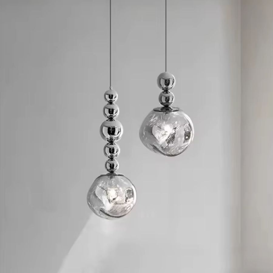 Deux suspensions à globe texturé et sphères chromées dessinent une composition sculpturale et contemporaine