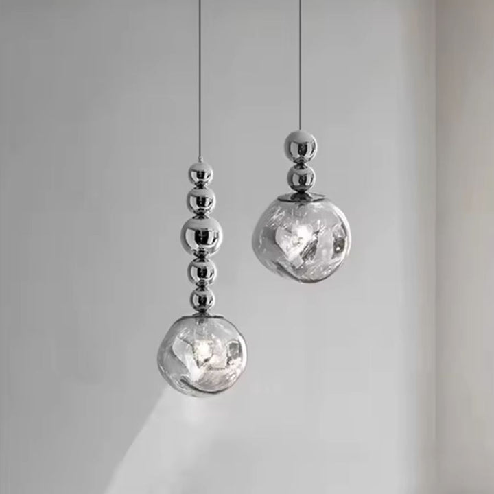 Deux suspensions à globe texturé et sphères chromées dessinent une composition sculpturale et contemporaine