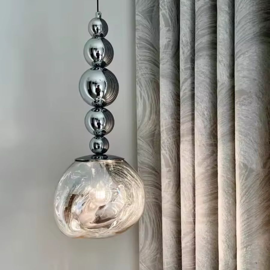 Cinq sphères chromées prolongent un globe texturé transparent pour une suspension élégante au style sculptural