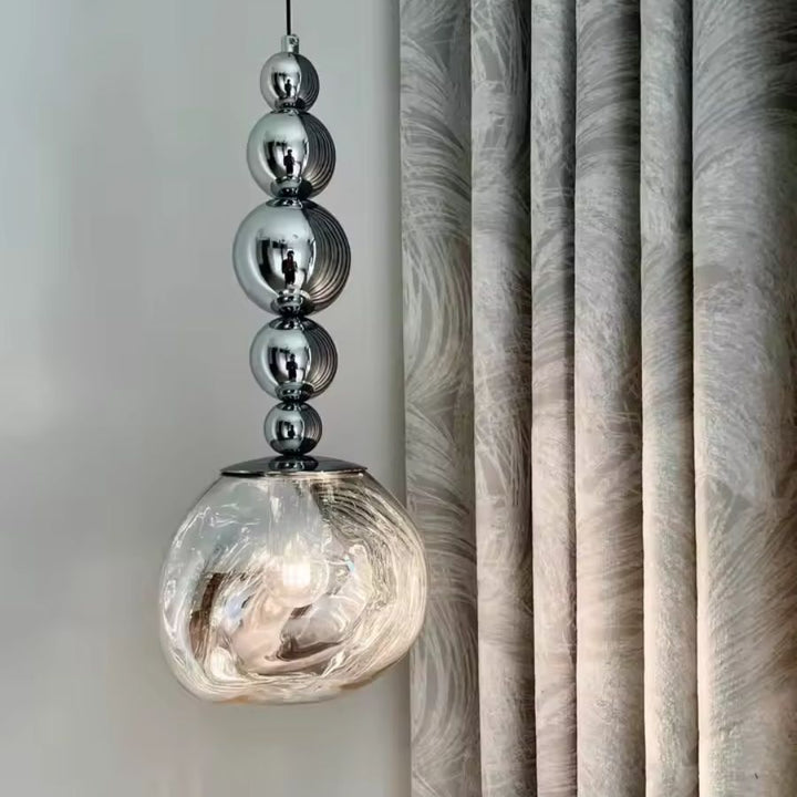 Cinq sphères chromées prolongent un globe texturé transparent pour une suspension élégante au style sculptural