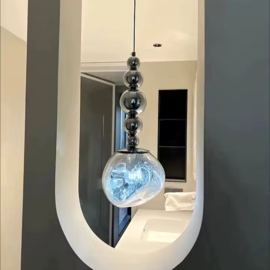 Dans un passage moderne, la suspension associe cinq sphères chromées à un globe transparent aux reflets lumineux