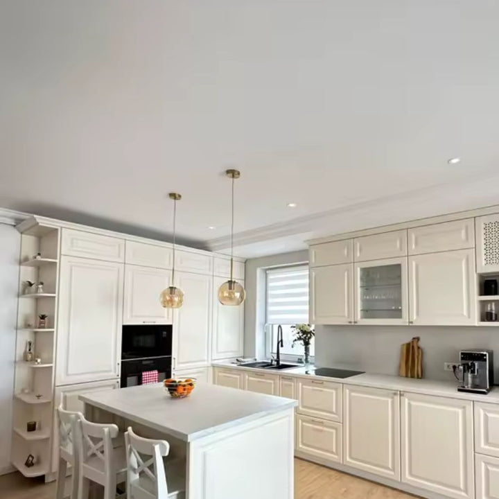 Duo de suspensions globe en verre ambré éclairant un îlot de cuisine dans un intérieur chic et lumineux