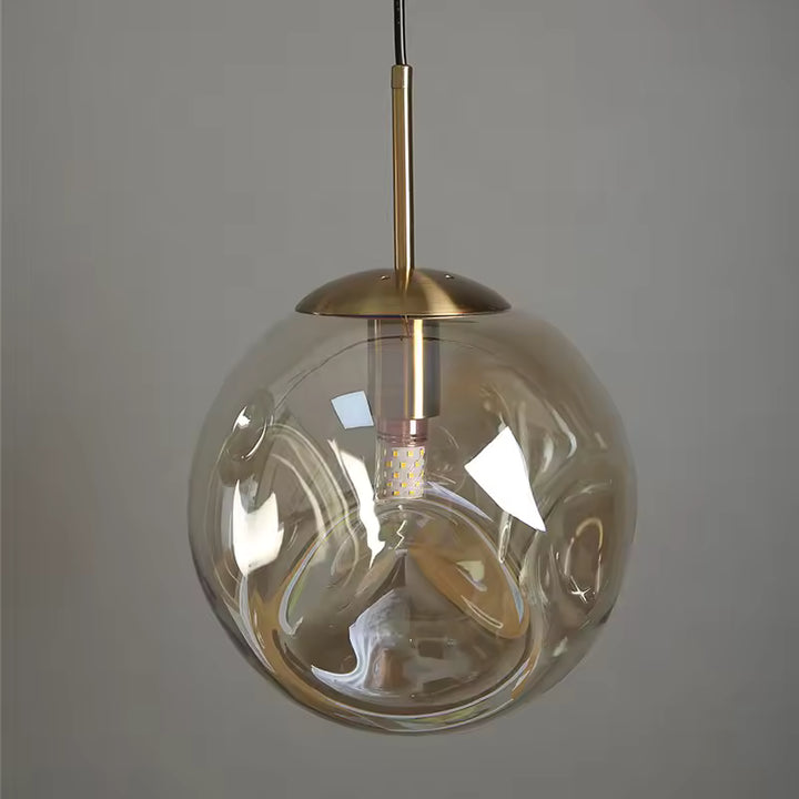 Suspension globe en verre ambré ondulé avec détails dorés, au design organique, élégant et contemporain