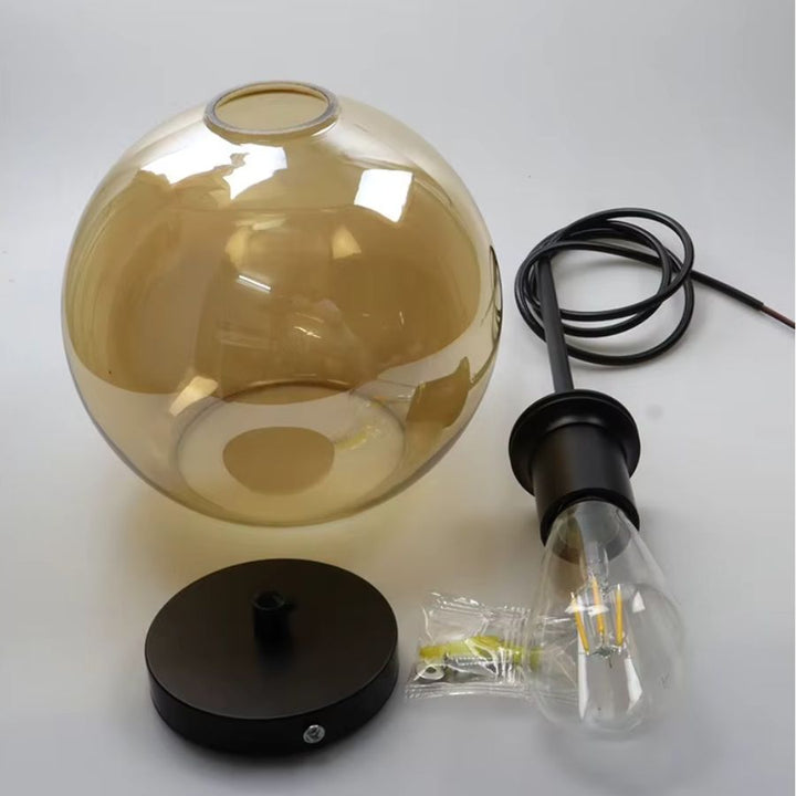 Globe en verre ambré avec structure noire et ampoule filament, détails de la suspension au style chaleureux