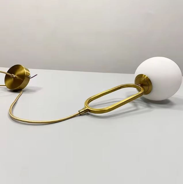 Suspension globe en verre blanc avec structure en laiton, luminaire épuré d’inspiration contemporaine aux lignes élégantes.