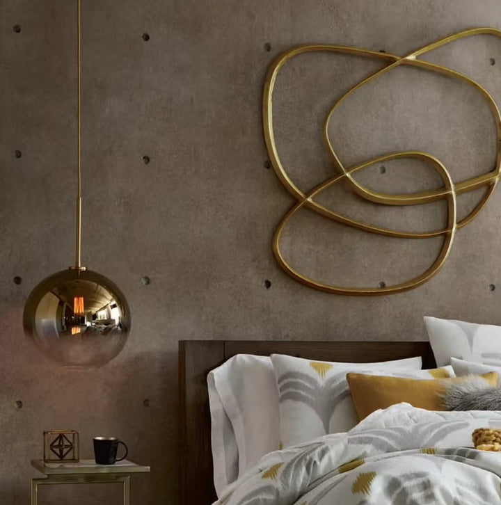 Près du lit, une suspension globe en verre fumé doré apporte une touche vintage et sophistiquée à la chambre