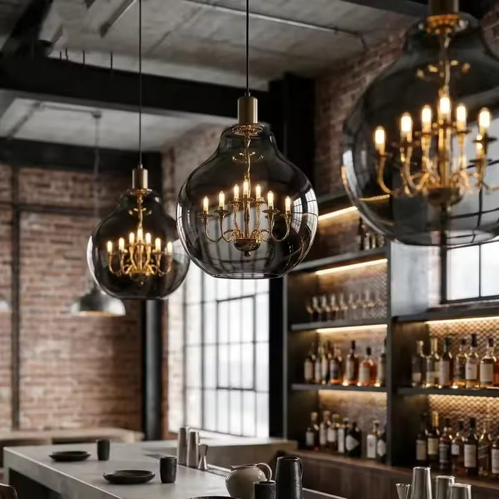Globes en verre fumé suspendus avec lustres dorés intérieurs, dans une ambiance chic entre vintage et industriel