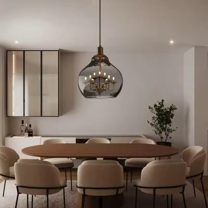 Globe en verre fumé avec lustre doré suspendu au-dessus d’une table, dans une salle à manger design et raffinée