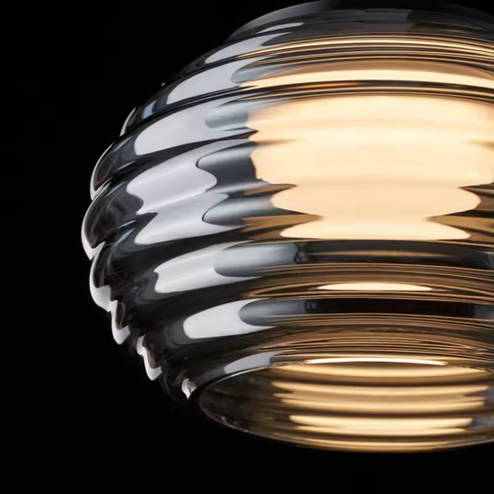 Gros plan sur un globe en verre fumé strié, aux reflets lumineux et au design rétro contemporain