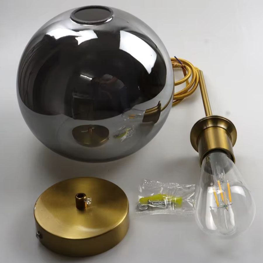 Globe en verre gris fumé avec finition dorée et ampoule apparente, au rendu chic et sophistiqué