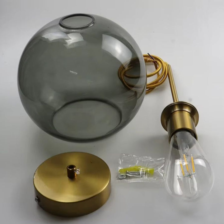 Suspension globe en verre gris avec structure dorée, montrant son pavillon, sa douille et son ampoule apparente