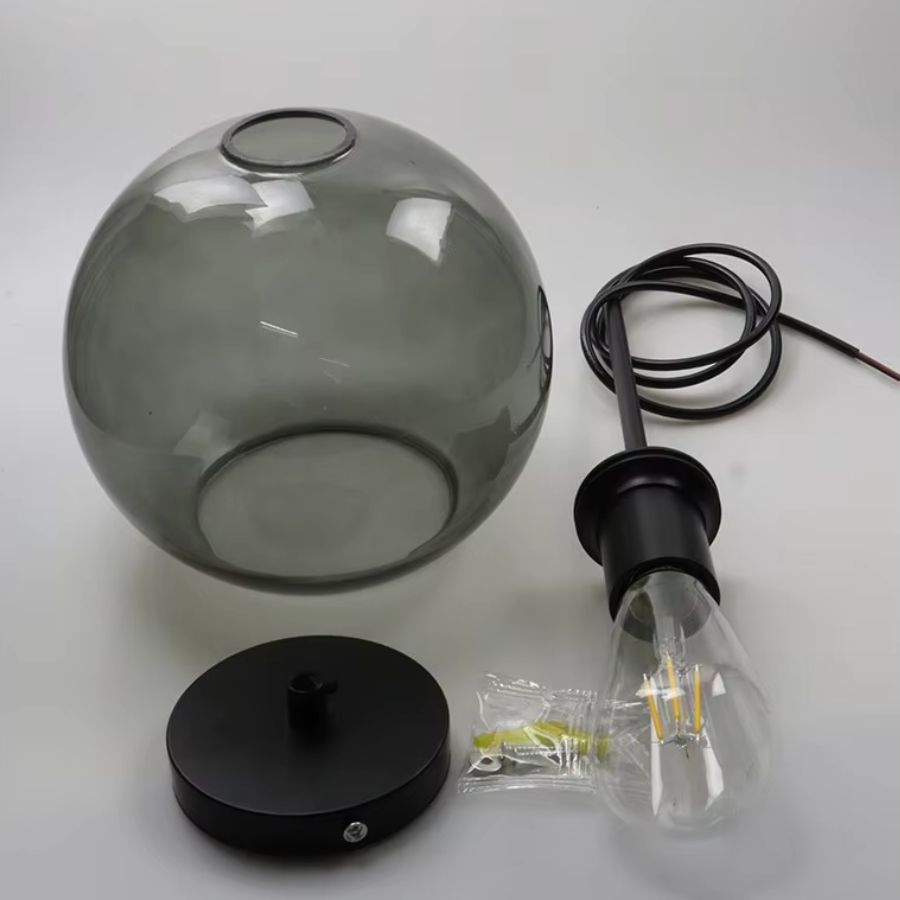 Suspension à globe en verre gris avec structure noire, présentée avec ses éléments de montage et son ampoule