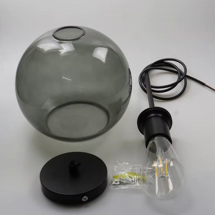 Suspension à globe en verre gris avec structure noire, présentée avec ses éléments de montage et son ampoule