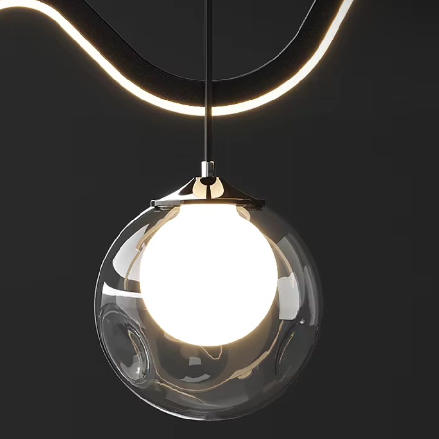 Détail d'un globe en verre transparent avec sphère lumineuse, suspendu sous une ligne LED courbe au style futuriste épuré.