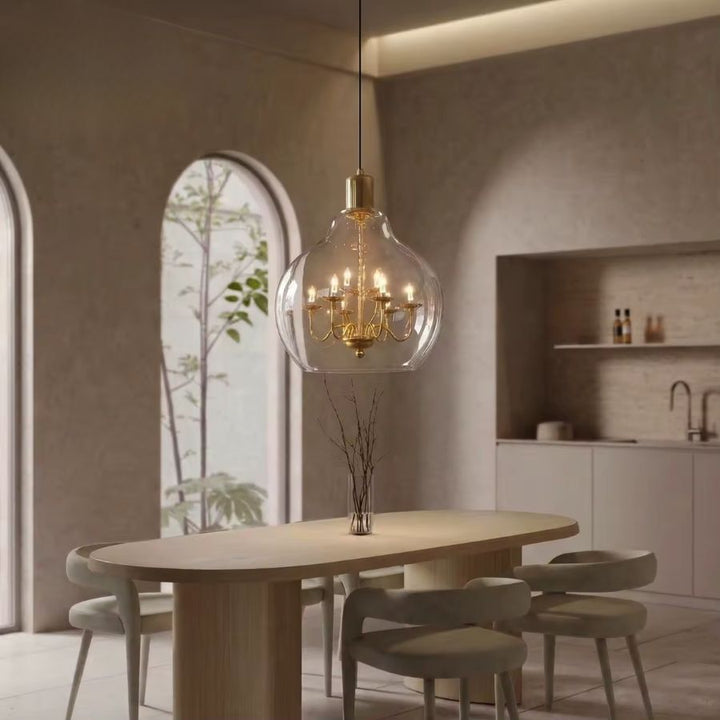Suspension globe en verre transparent avec lustre doré, au-dessus d’une table dans un intérieur chic et épuré