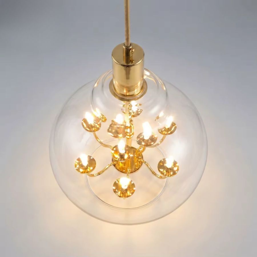 Vue de dessus d’une suspension globe en verre transparent révélant un lustre doré à plusieurs lumières
