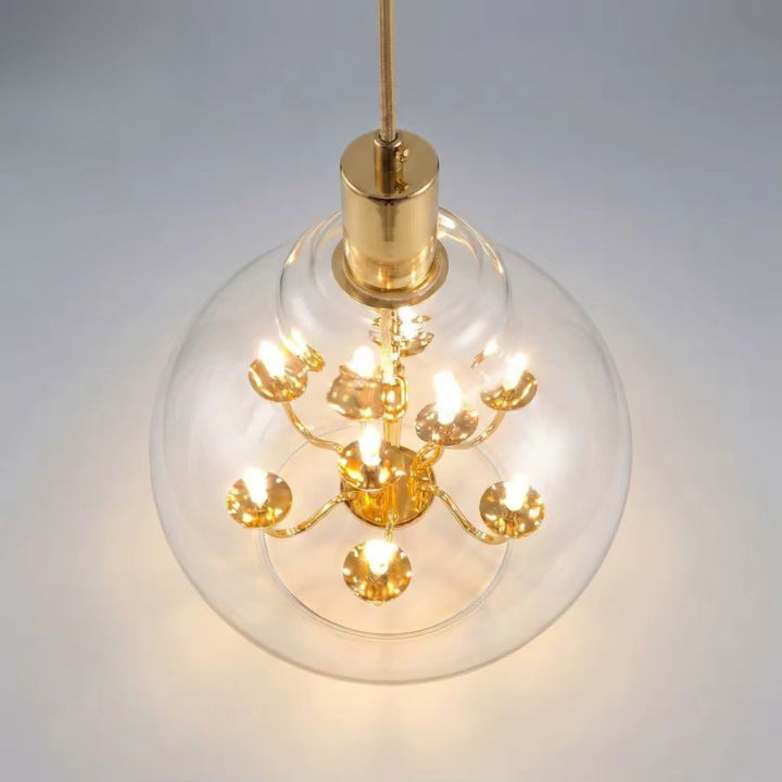 Vue de dessus d’une suspension globe en verre transparent révélant un lustre doré à plusieurs lumières
