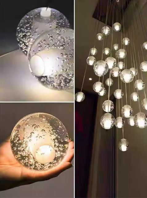 Suspension en cascade de globes en verre bullé effet cristal, création lumineuse design pour grand volume intérieur.