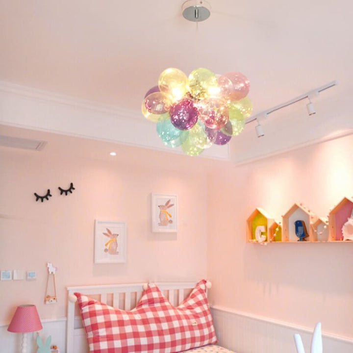 Suspension poétique en verre coloré translucide installée dans une chambre chaleureuse aux tons roses.