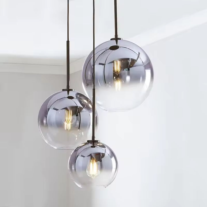Trois globes en verre dégradé composent une suspension élégante au style contemporain et légèrement rétro