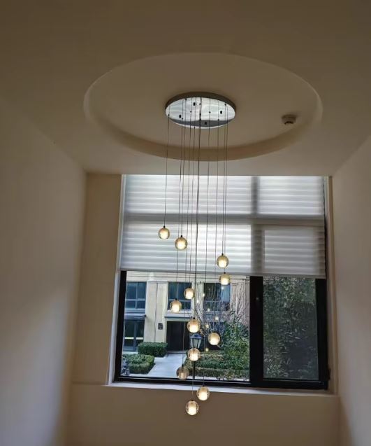 Suspension à globes en verre suspendus pour entrée avec plafond travaillé, éclairage design chaleureux et contemporain.