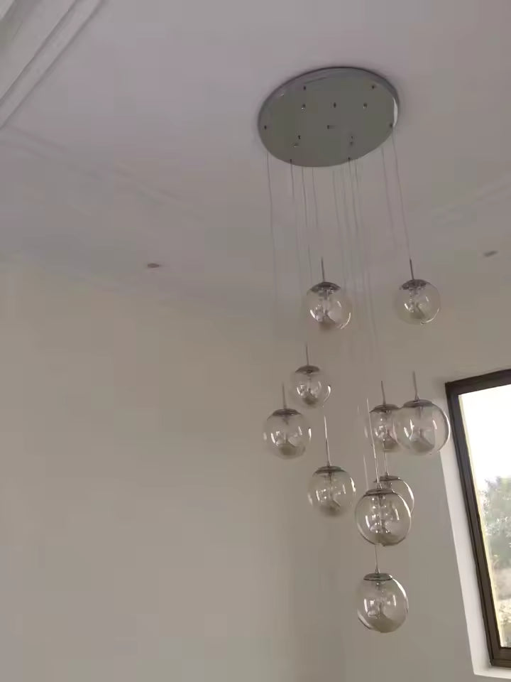 Suspension à globes en verre transparent éteinte, silhouette aérienne et design épuré aux lignes contemporaines