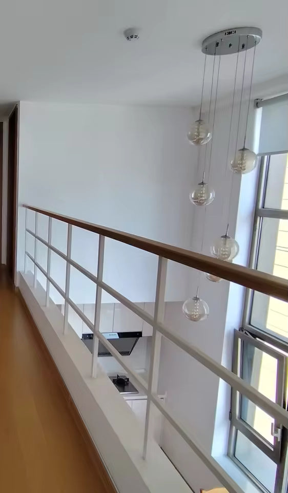 Suspension à globes en verre étagés dans un vide sur séjour, design minimaliste adapté à une mezzanine