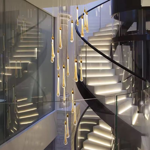 Suspension gouttes dorées LED dans un escalier en colimaçon contemporain, sublimant l’espace avec un éclairage architectural saisissant.