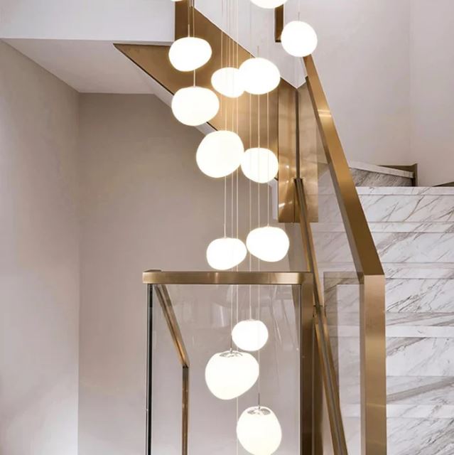 Grande suspension cage d'escalier ornée de boules lumineuses blanche, parfaite pour un intérieur en marbre.