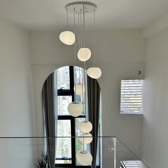 Suspension grappe blanche pour escalier à haut plafond, luminaire minimaliste aux globes lumineux suspendus.
