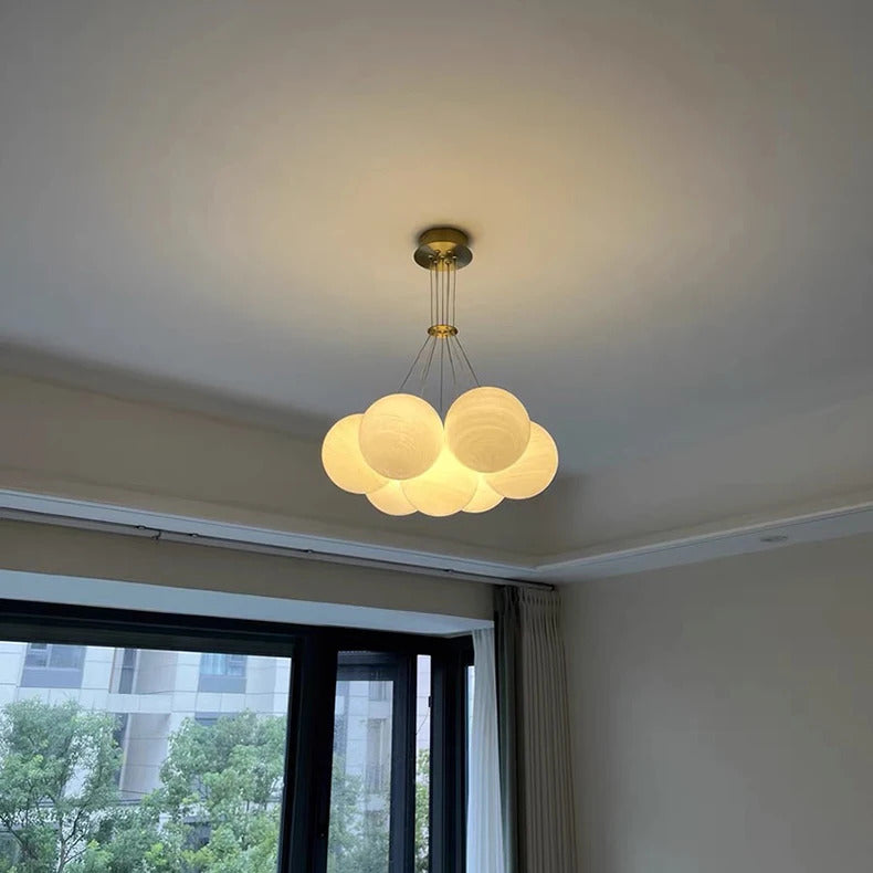 Suspension en grappe de globes en verre opalin allumés avec finition en laiton brossé, au style design contemporain.