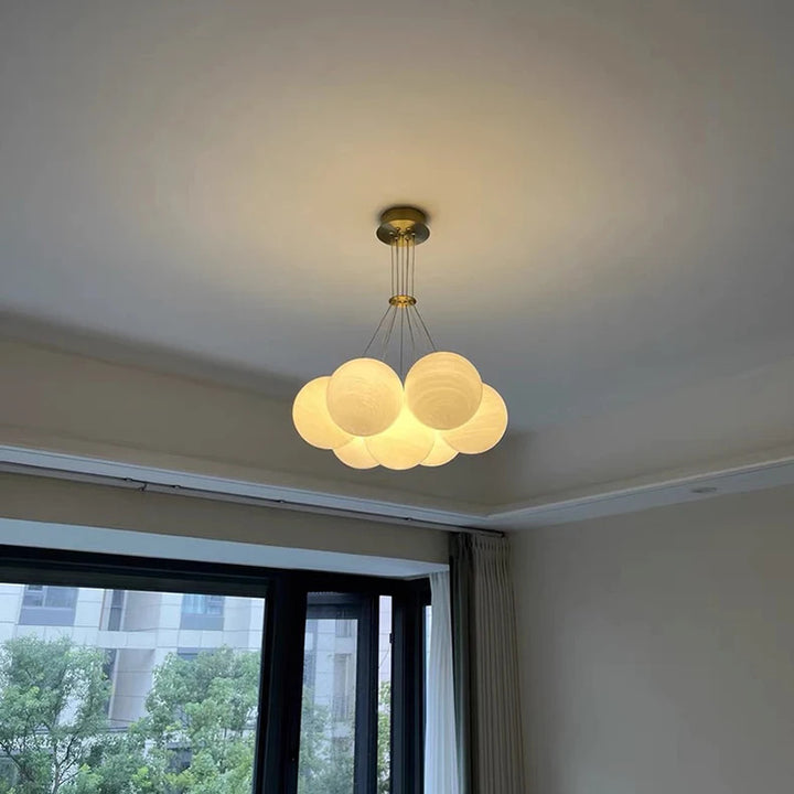 Suspension en grappe de globes en verre opalin allumés avec finition en laiton brossé, au style design contemporain.