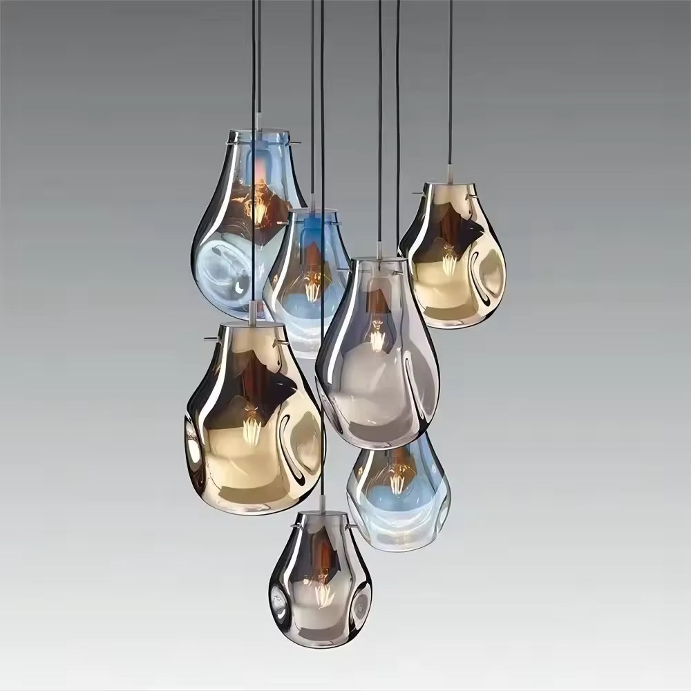 Assemblage de sept suspensions en verre soufflé bleu, fumé et ambré aux formes organiques, créant un lustre sculptural.