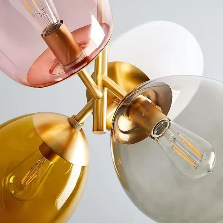 Vue rapprochée d’une suspension rétro à verres rose, ambre, fumé et opalin avec ampoules à filament apparentes