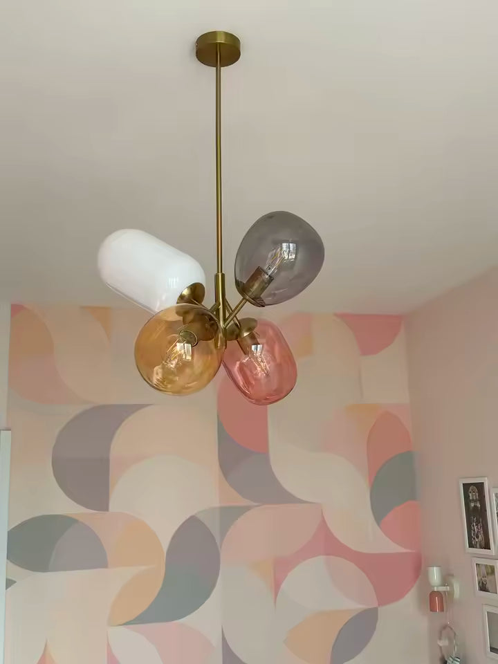 Suspension rétro en verre coloré à globes rose, ambre, fumé et opalin dans un intérieur pop aux tons pastel